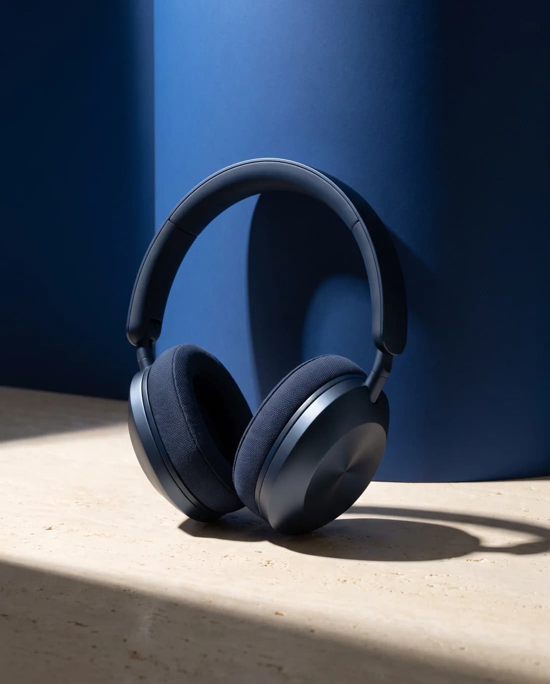 Navy headphones photographed against sculptural blue architecture